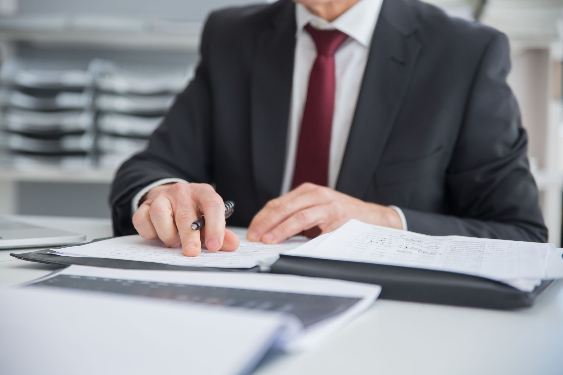 Close-up of a businessman reviewing compliance documents at an office desk.